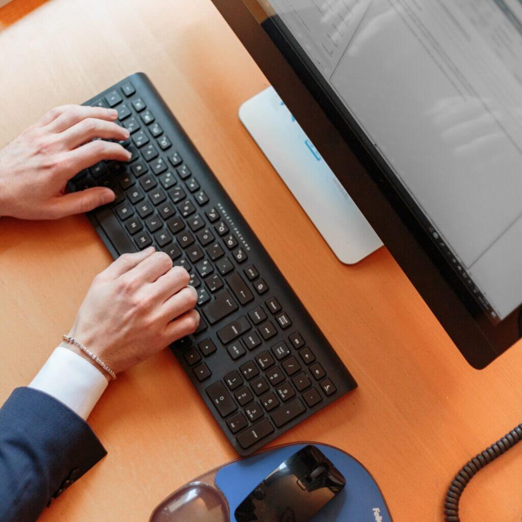 Une personne tape sur un clavier d'ordinateur illustrant la prestation d'espace numérique et d'aide à l'utilisation d'un ordinateur pour les démarches en ligne proposé par le théâtre social itinérant le bazar culturel