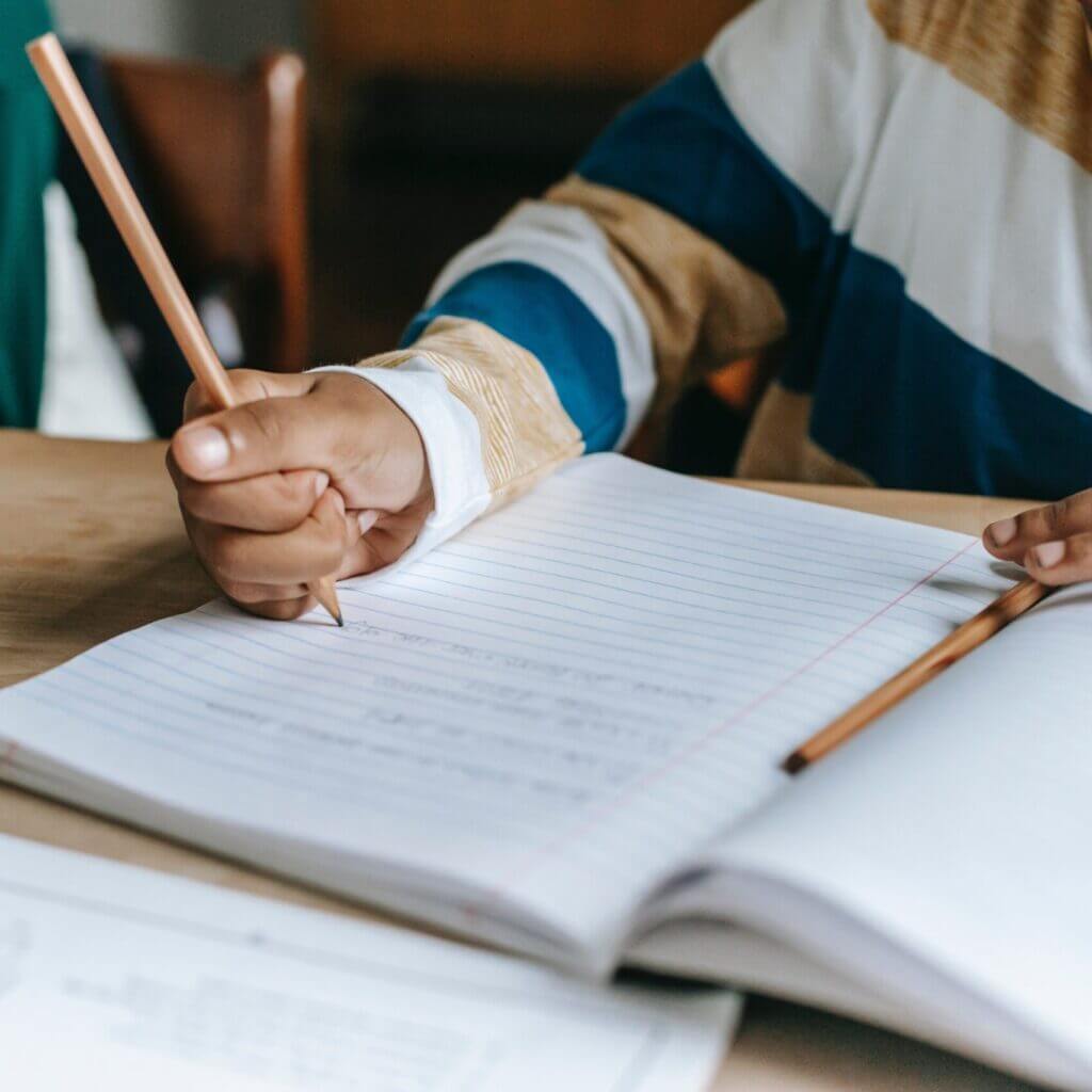Un enfant faisant ses devoirs grâce à la prestation d'accompagnement au soutien scolaire et aide aux devoirs proposé par le théâtre social itinérant le bazar culturel