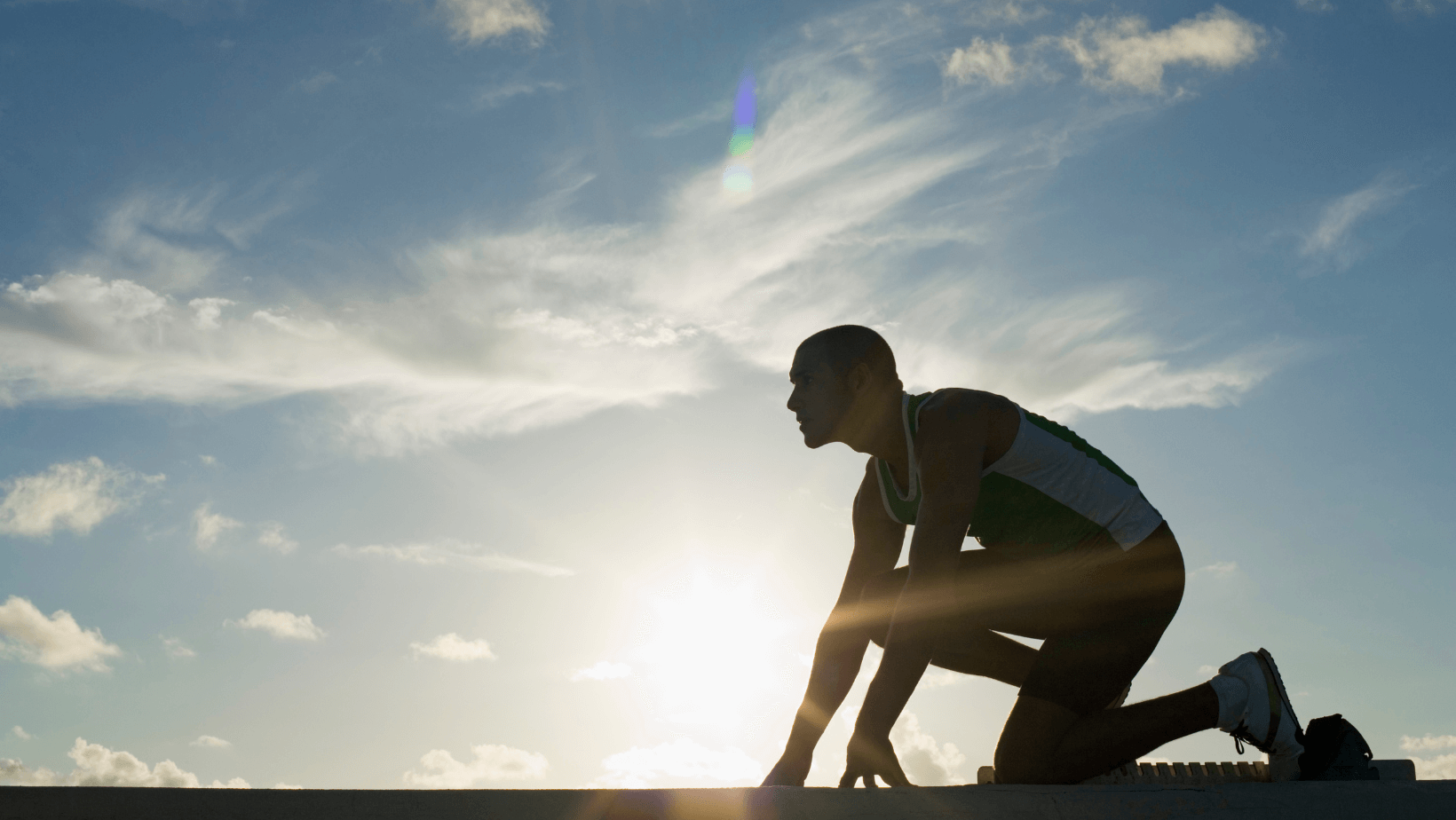 Un homme dans les starting blocks, prêt à courir.